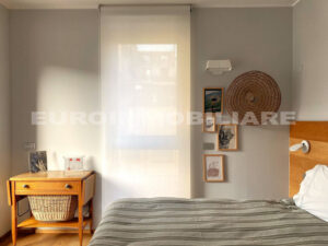 Camera da letto accogliente in un pentalocale a Milano con arredi in legno e decorazioni murali artistiche.