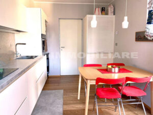 Cucina moderna e luminosa in un appartamento a Milano, con sedie rosse e un design pulito.