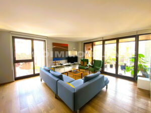 Ampio e luminoso soggiorno in un pentalocale a Milano, con divani blu, decorazioni moderne e accesso al balcone.