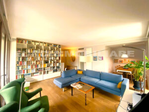 Soggiorno con ampia libreria e divani confortevoli in un appartamento.
