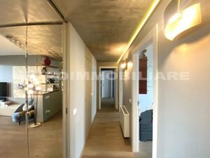 Corridoio con pavimento in parquet e pareti bianche in un quadrilocale a Milano.